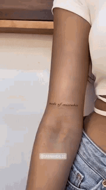 a woman with a tattoo on her arm that says made of mistakes .