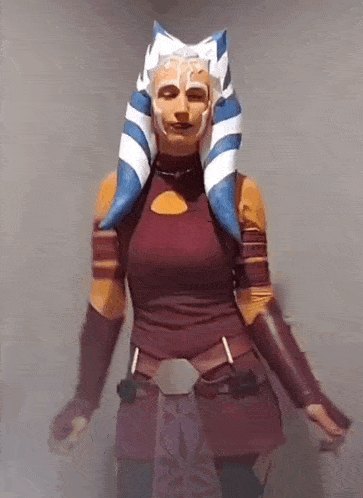 a woman in a costume is standing in front of a white wall .