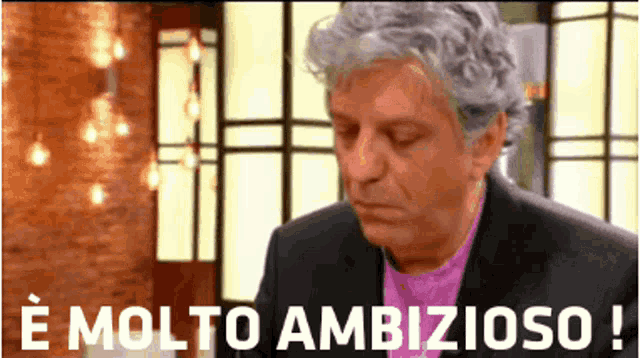 a man in a suit and purple shirt says molto ambitioso !