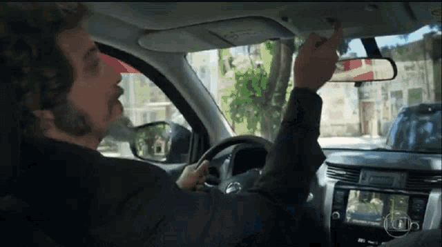 a man is driving a car and pointing at something