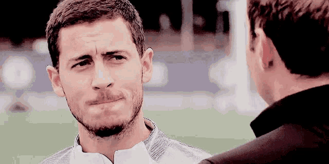 a man with a beard is making a funny face while talking to another man .