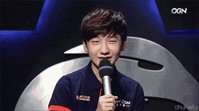 a young man is holding a microphone with ogn written on the screen behind him