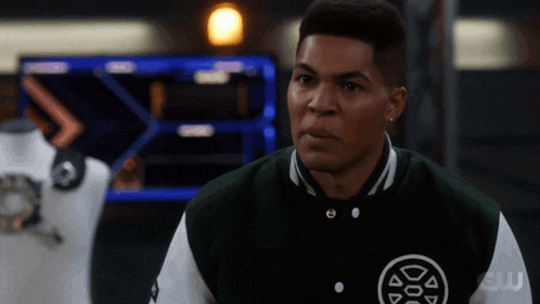 a man wearing a green and white varsity jacket with a logo on it