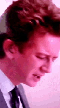 a close up of a man 's face with a pink background .