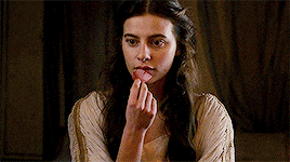 a woman is holding a piece of food in her hand and eating it .