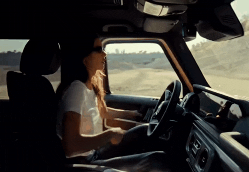 a woman is sitting in the driver 's seat of a vehicle