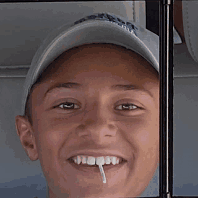 a young boy wearing a hat that says ' boston ' on it smiles