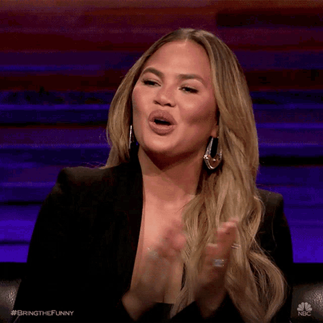 a woman applauds while wearing a black jacket and earrings ..