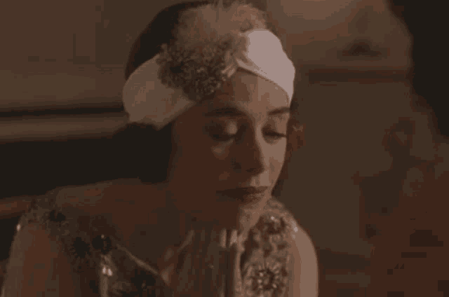 a woman wearing a headband with feathers on it looks down