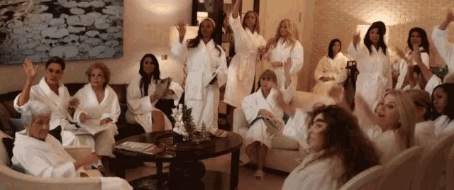 a group of women in white robes are sitting in a room