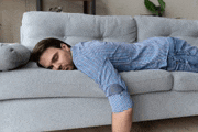 a man is sleeping on a couch with his head on the arm rest .