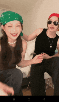 a woman wearing sunglasses and a green bandana laughs with another woman