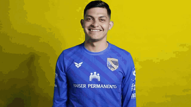 a man wearing a blue kaiser permanente shirt smiles for the camera