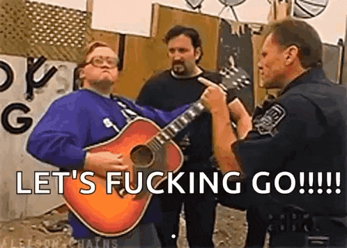 a man is playing a guitar in front of a police officer while another man looks on .