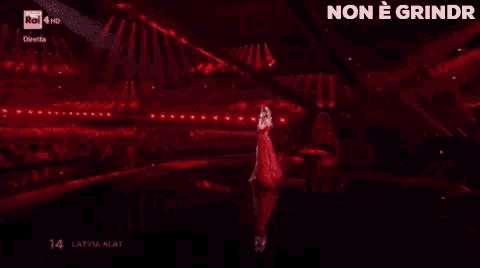 a woman in a long red dress is singing into a microphone on a stage .