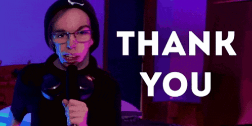 a person holding a microphone in front of a thank you sign