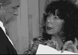 a black and white photo of a man and woman talking