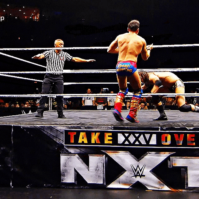 wrestlers in a ring with a sign that says ' take xxx love '