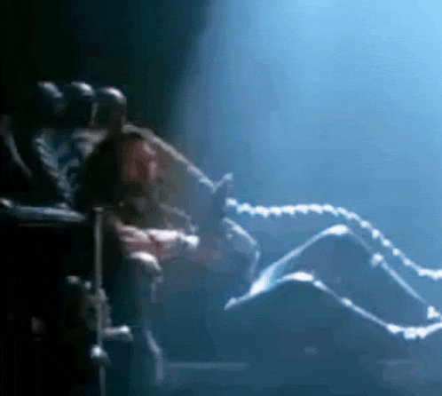 a group of people are sitting in chairs in a dark room watching a show .