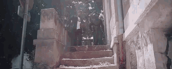 a man in a suit is walking up the stairs of an abandoned building .