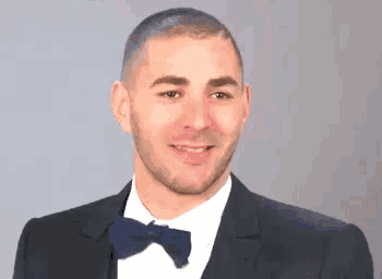 a man in a suit and bow tie is smiling and looking at the camera .