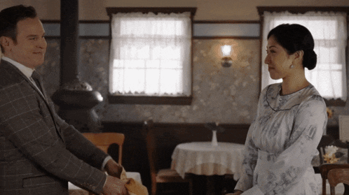 a man in a suit and tie is shaking hands with a woman
