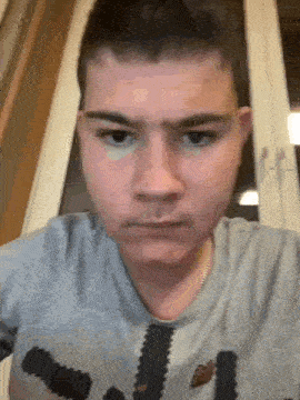 a young man is making a funny face while wearing a grey shirt .
