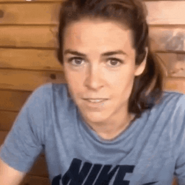 a woman wearing a blue nike shirt is smiling