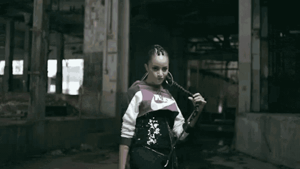 a woman is standing in a dark room wearing a nike shirt and earrings .