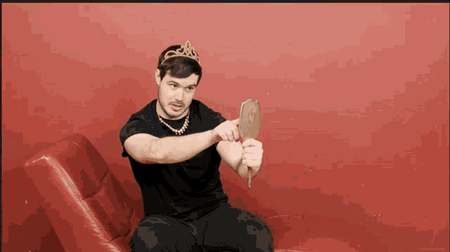 a man wearing a tiara looks at himself in a hand mirror