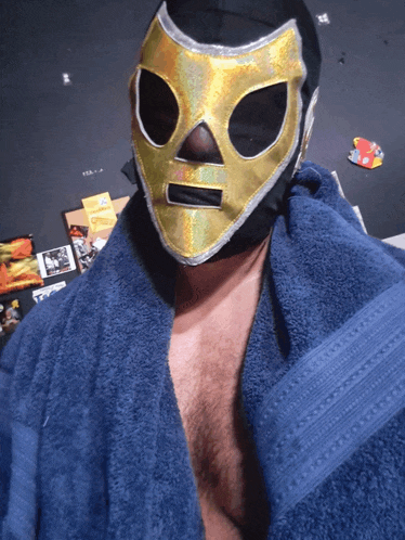 a man wearing a gold mask is wrapped in a blue robe