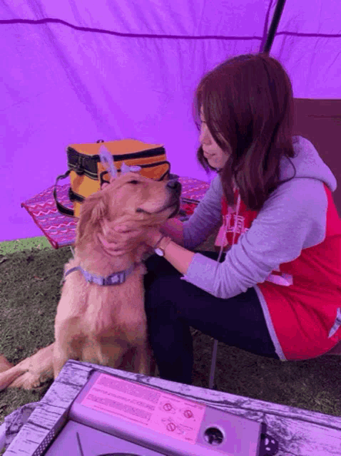 a woman petting a dog while wearing a red shirt that says ' abercrombie & fitch ' on the front