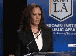 a woman giving a speech in front of a sign that says la