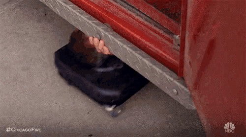 a person is hiding underneath a fire truck .