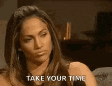 a woman is sitting on a couch and talking to someone while a man says `` take your time '' .