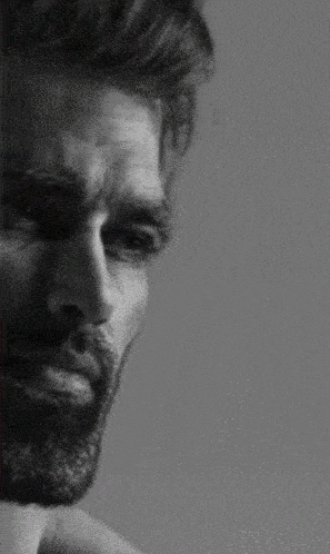 a black and white photo of a man with a beard looking at the camera