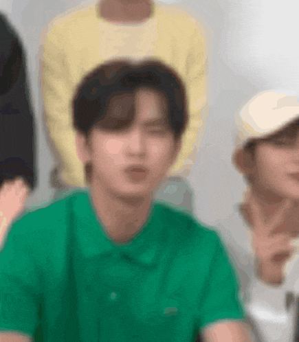 a blurry picture of a man wearing a green shirt and a white hat .