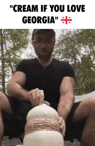 a man in a black shirt is kneeling down and holding a white object with the words " cream if you love georgia " on the top
