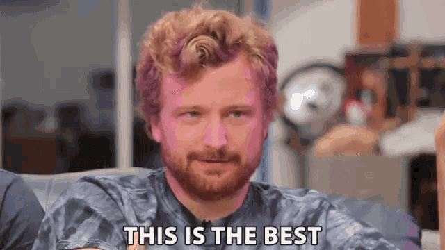 a man with a beard is sitting on a couch and says this is the best