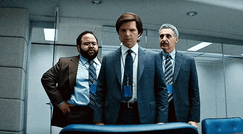three men in suits and ties are standing next to each other in a room