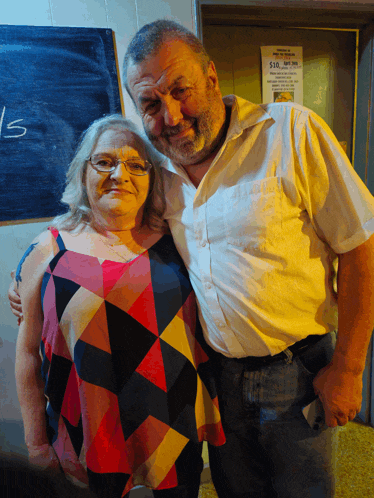 a man and a woman are posing for a picture in front of a sign that says 15