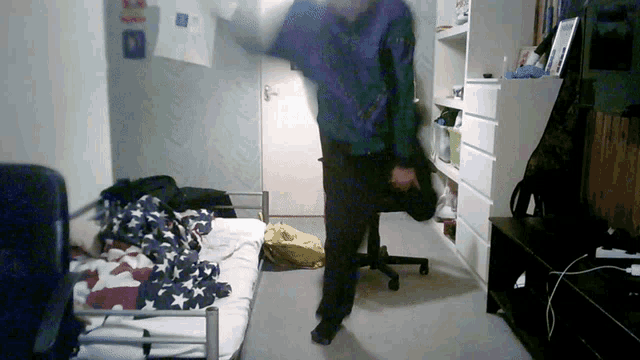 a man in a blue jacket is standing in a room with a poster on the wall that says ' i love you '