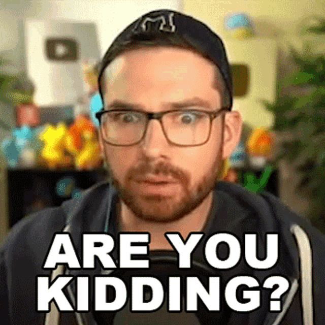 a man with glasses and a beard is wearing a hat and saying are you kidding ?
