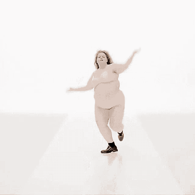 a woman is dancing on a white surface with her hair blowing in the wind