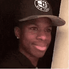 a man wearing a black hat with the word new york on it is smiling .
