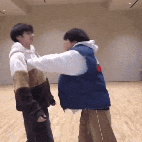 two people are standing next to each other on a wooden floor .
