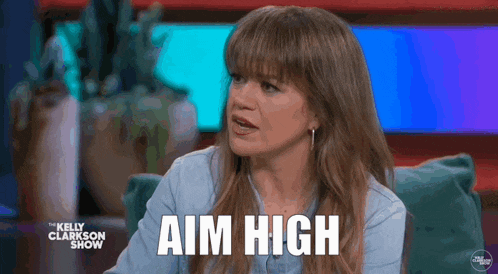 a woman is sitting on a couch with the words aim high written on her face .