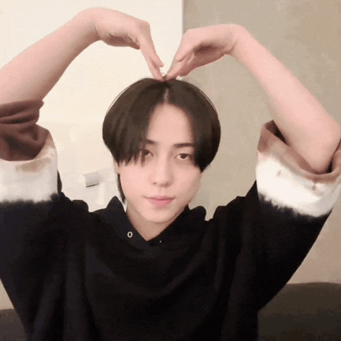 a person making a heart shape with their hands over their head