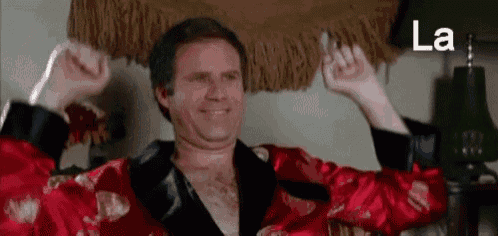 a man in a red robe is flexing his muscles and smiling .