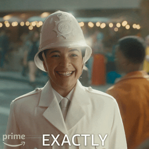 a woman wearing a helmet smiles in front of a sign that says " exactly "
